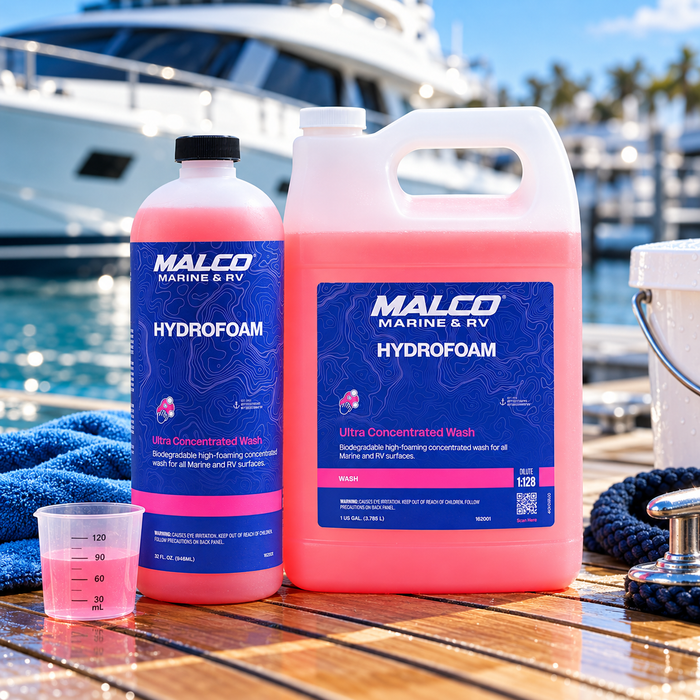 Malco HydroFoam 32 oz bottle and gallon jug with a measuring cup on a dock beside a boat.