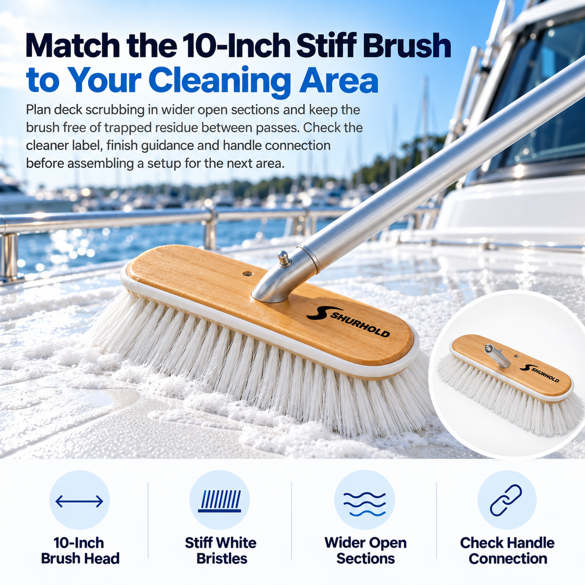 Shurhold 990 10-inch stiff deck brush with white bristles and a wooden head scrubbing a soapy white yacht deck.